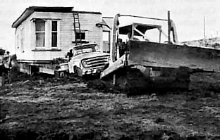 A buldozer is needed to tow the house to its resting place