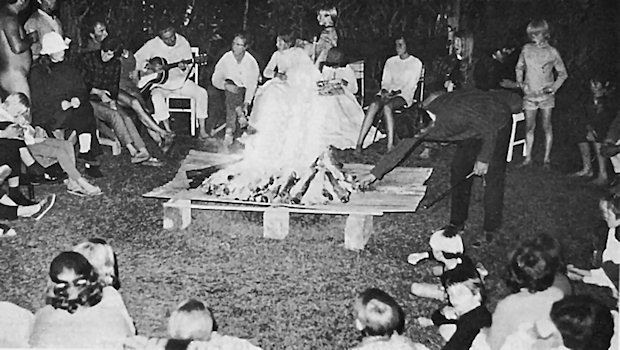 Members round a fire at night